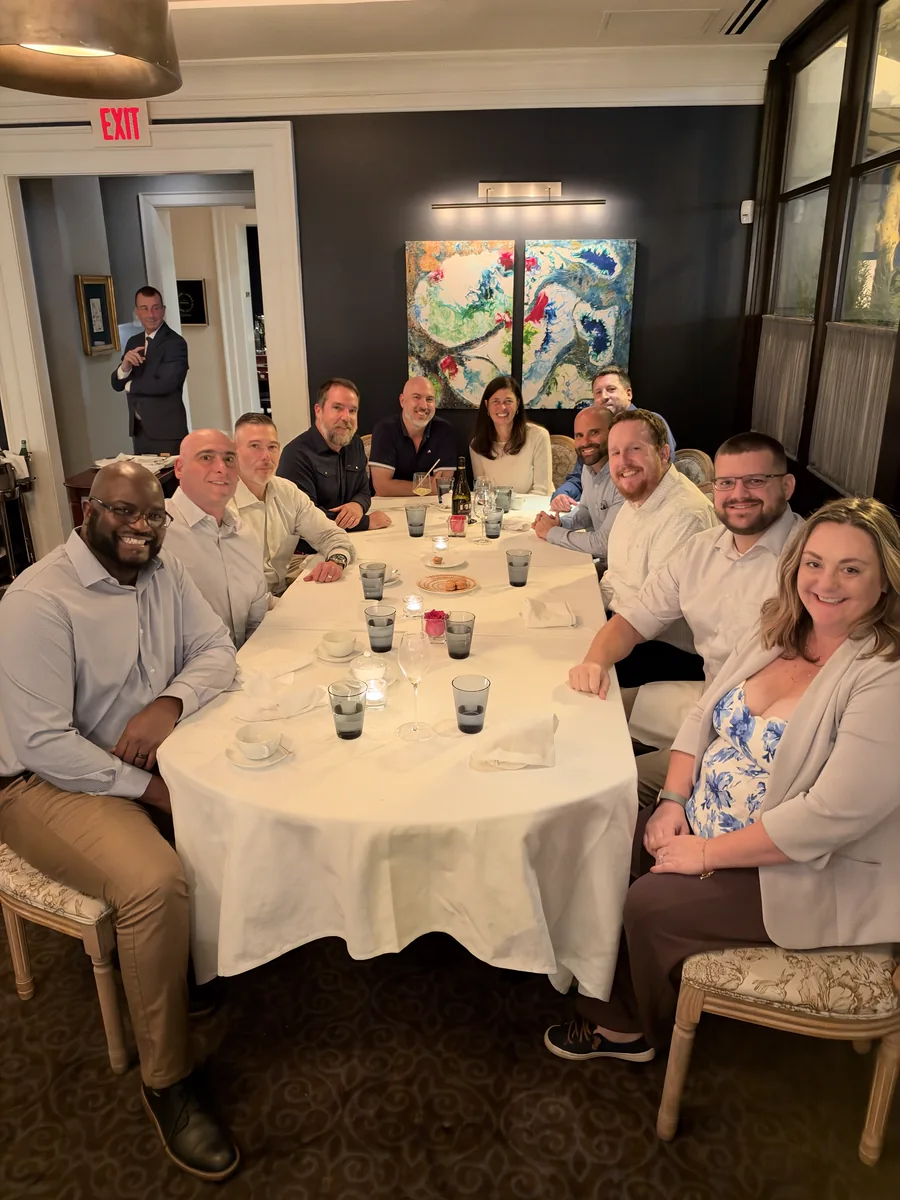 Helion Technologies team members smiling around a table at a team dinner